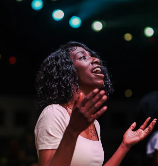 Woman in open-handed worship at AYAC USA
